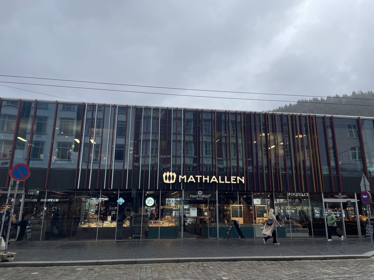 Fachada moderna de cristal del mercado gastronómico Mathallen y Fisketorget en Bergen, Noruega, en un día nublado