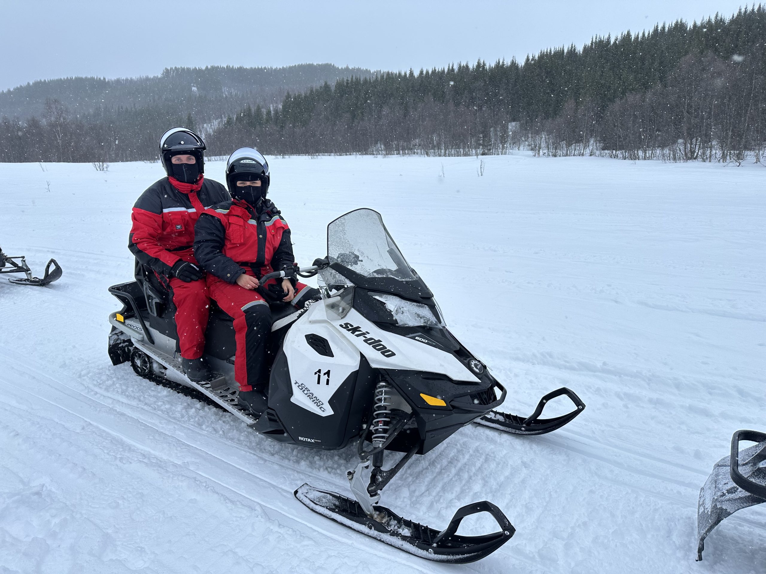 Excursión en moto de nieve en Noruega con paisaje nevado y bosque al fondo