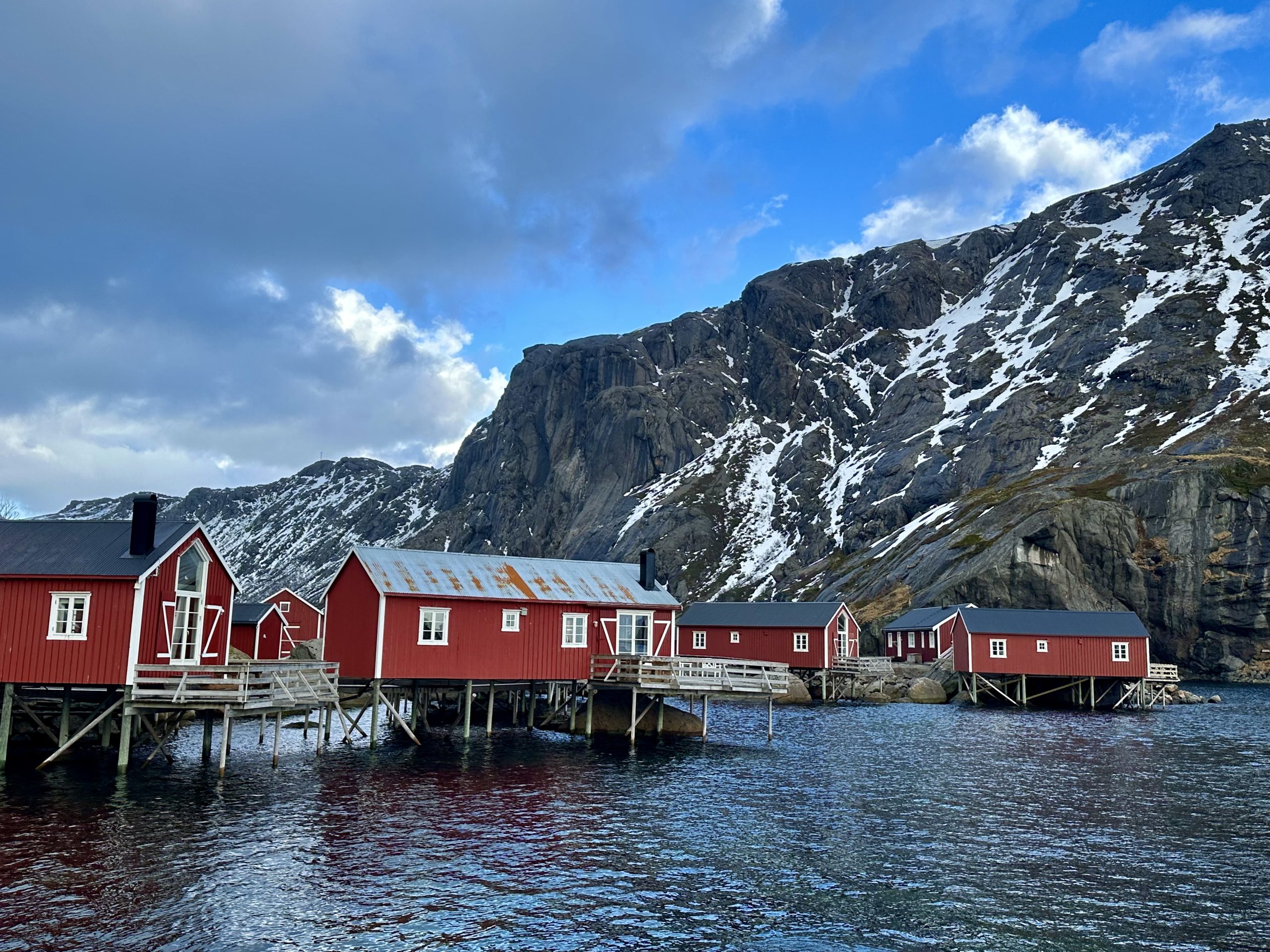 Cabañas tradicionales de Nusfjord frente al fiordo y montañas nevadas de Lofoten