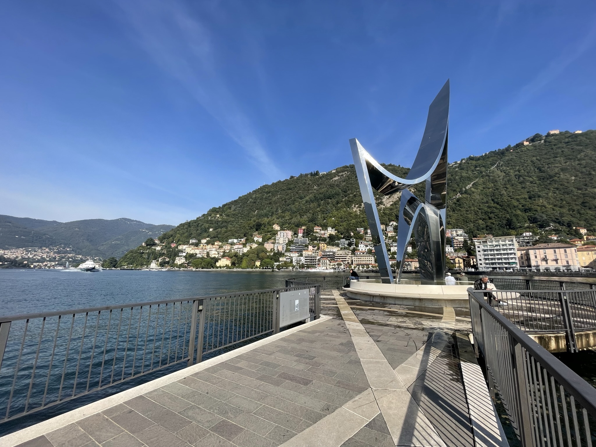 Escultura Life Electric en el Lago di Como con montañas y ciudad al fondo