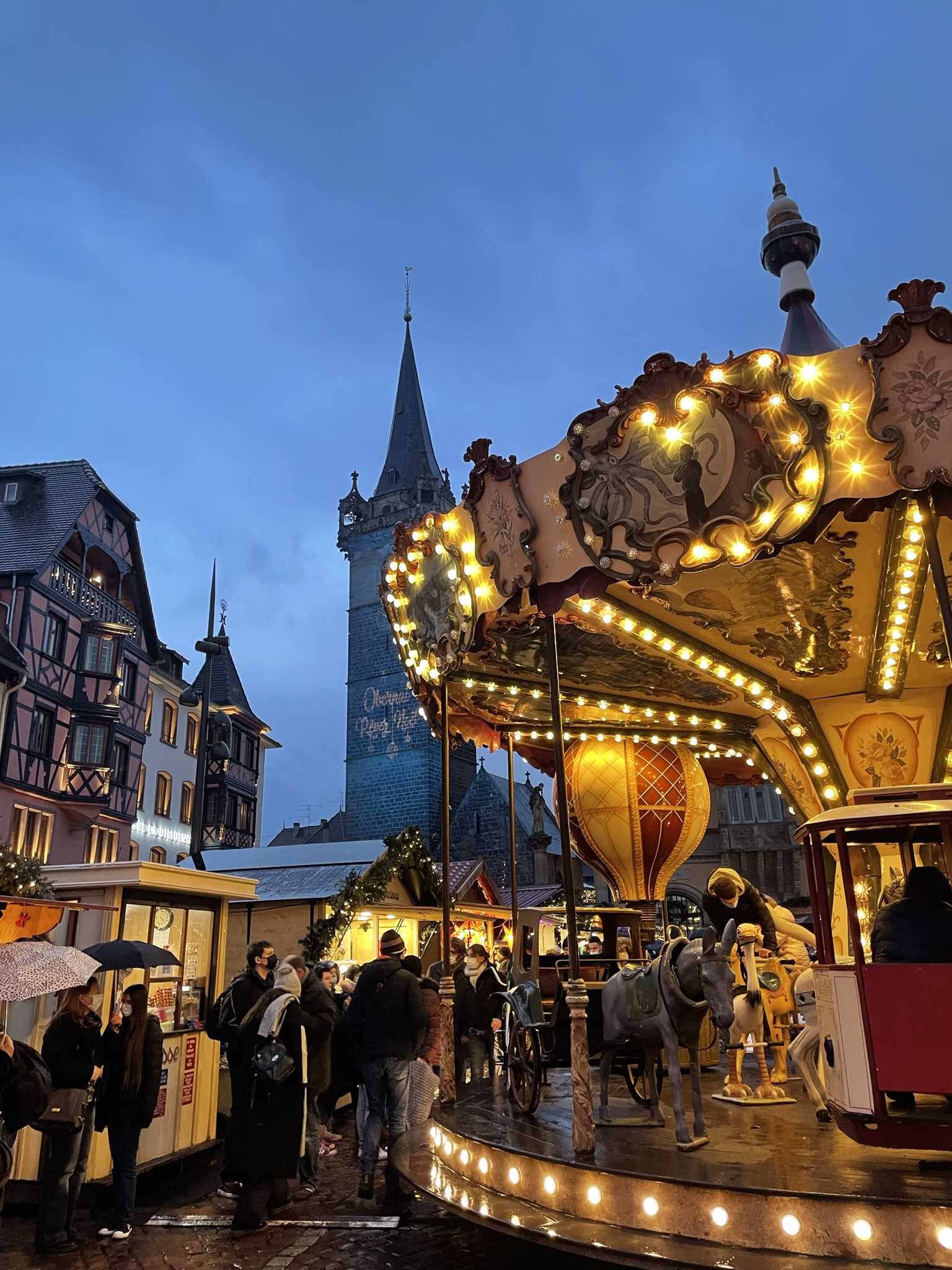 Carrusel iluminado en el mercado de Navidad de Obernai con la iglesia al fondo