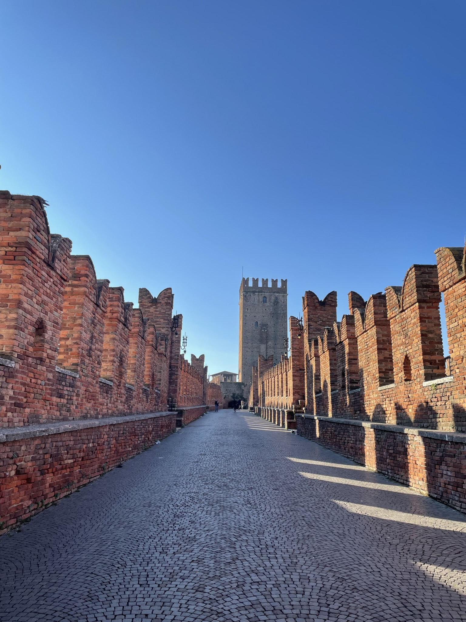 Interior del Puente de Castelvecchio en Verona, con sus murallas almenadas de ladrillo rojo y torres medievales.