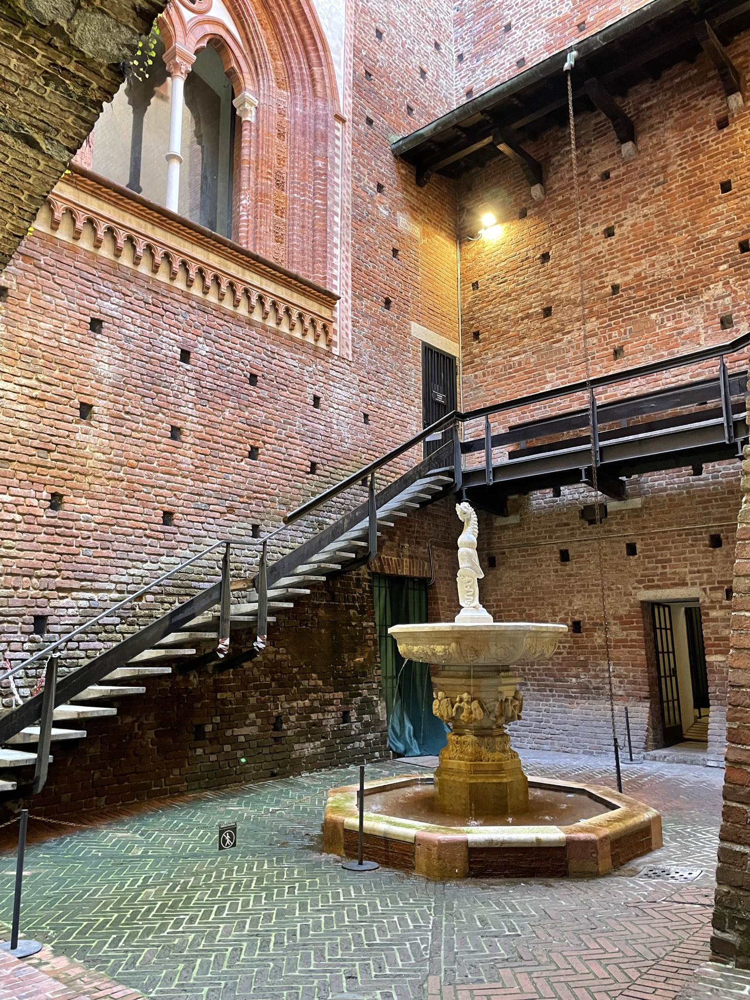 Patio interior del Castillo Sforzesco de Milán con fuente y paredes de ladrillo