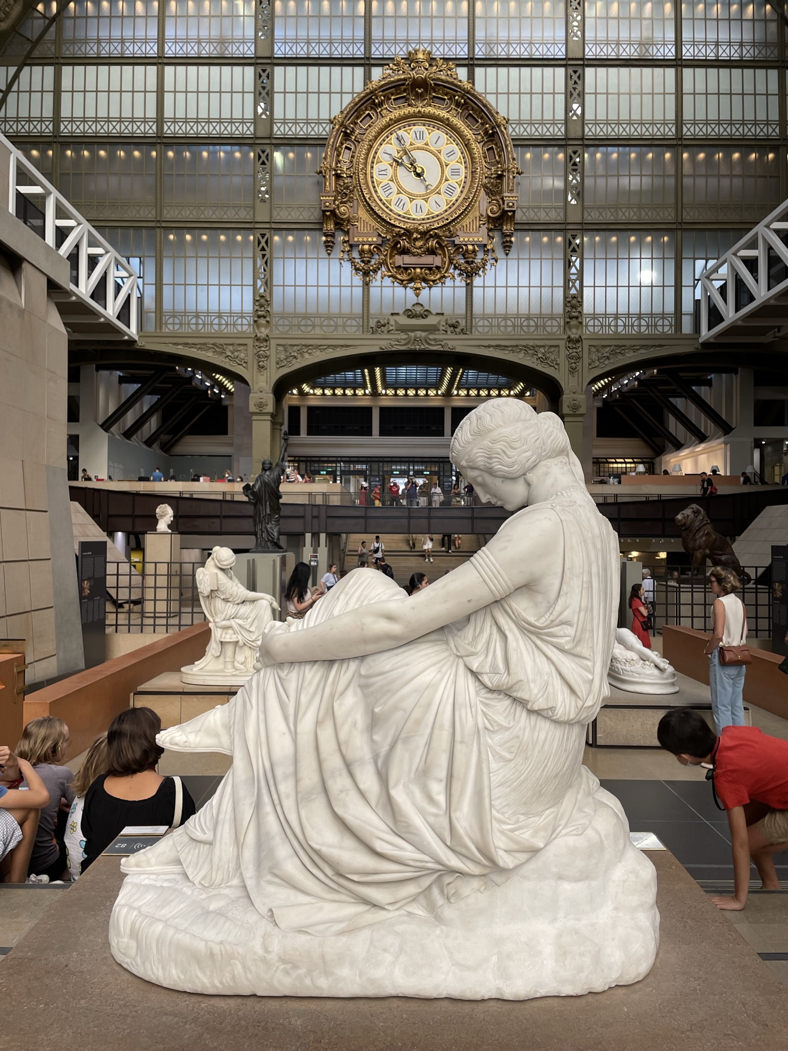 Esculturas del Museo de Orsay en París con el reloj principal al fondo