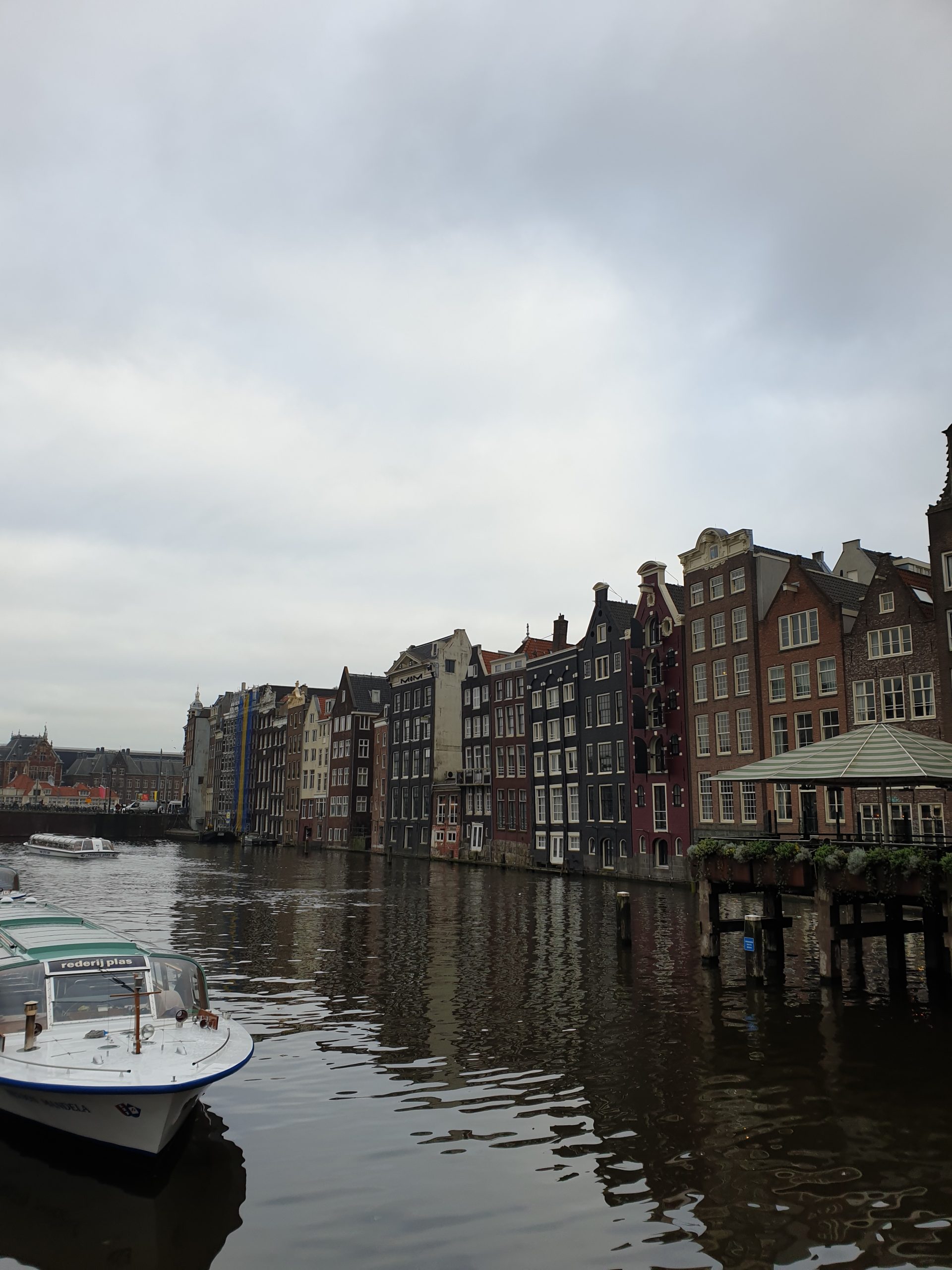Canal Damrak con casas típicas y barco en Ámsterdam
