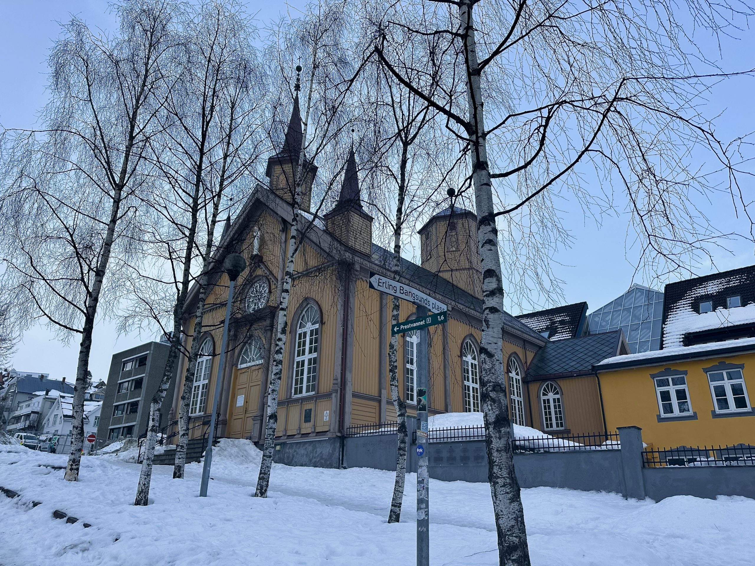 Iglesia de madera en Tromsø rodeada de nieve y abedules