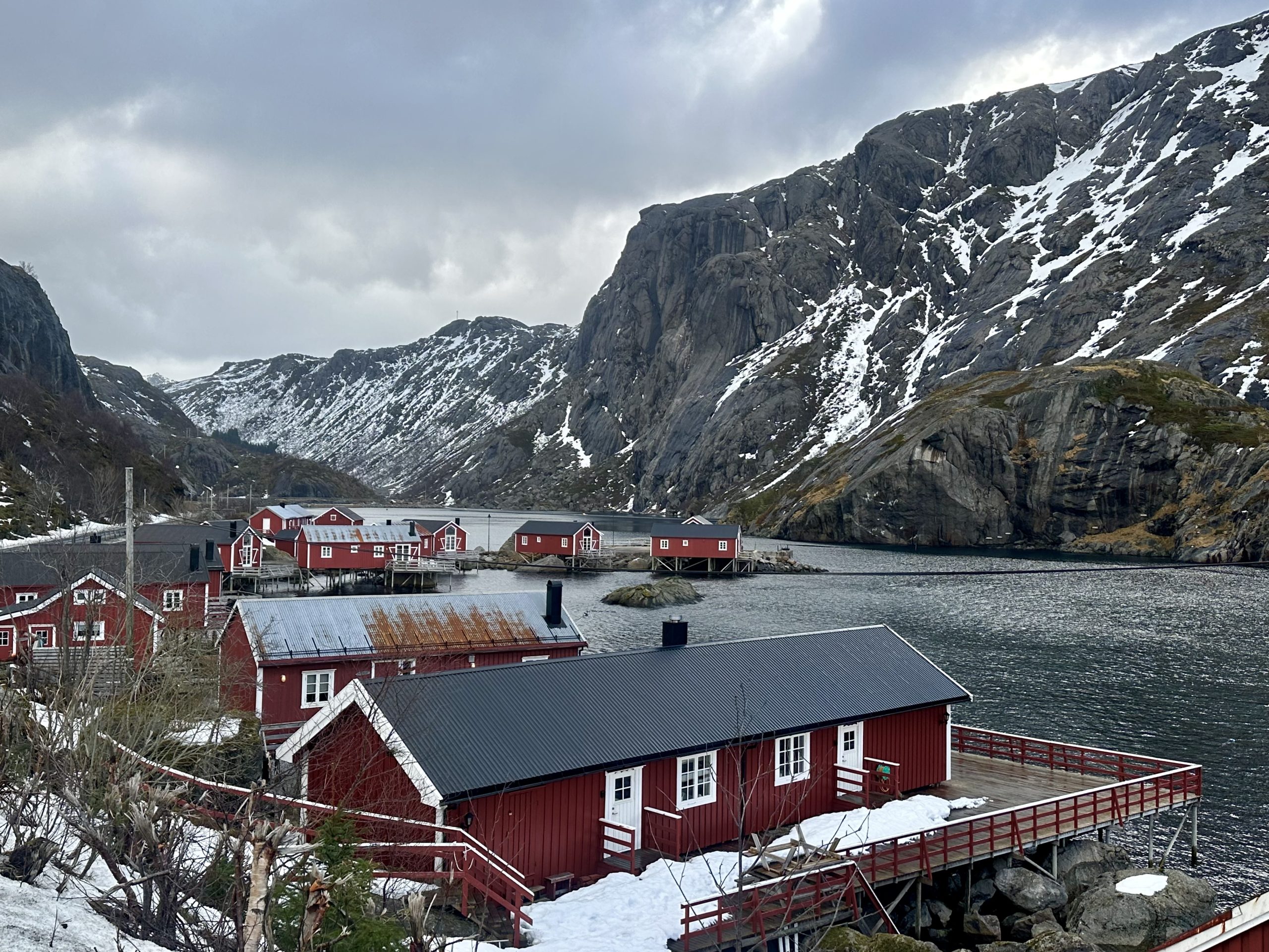 Cabañas rojas de Nusfjord junto al fiordo y montañas nevadas en Lofoten