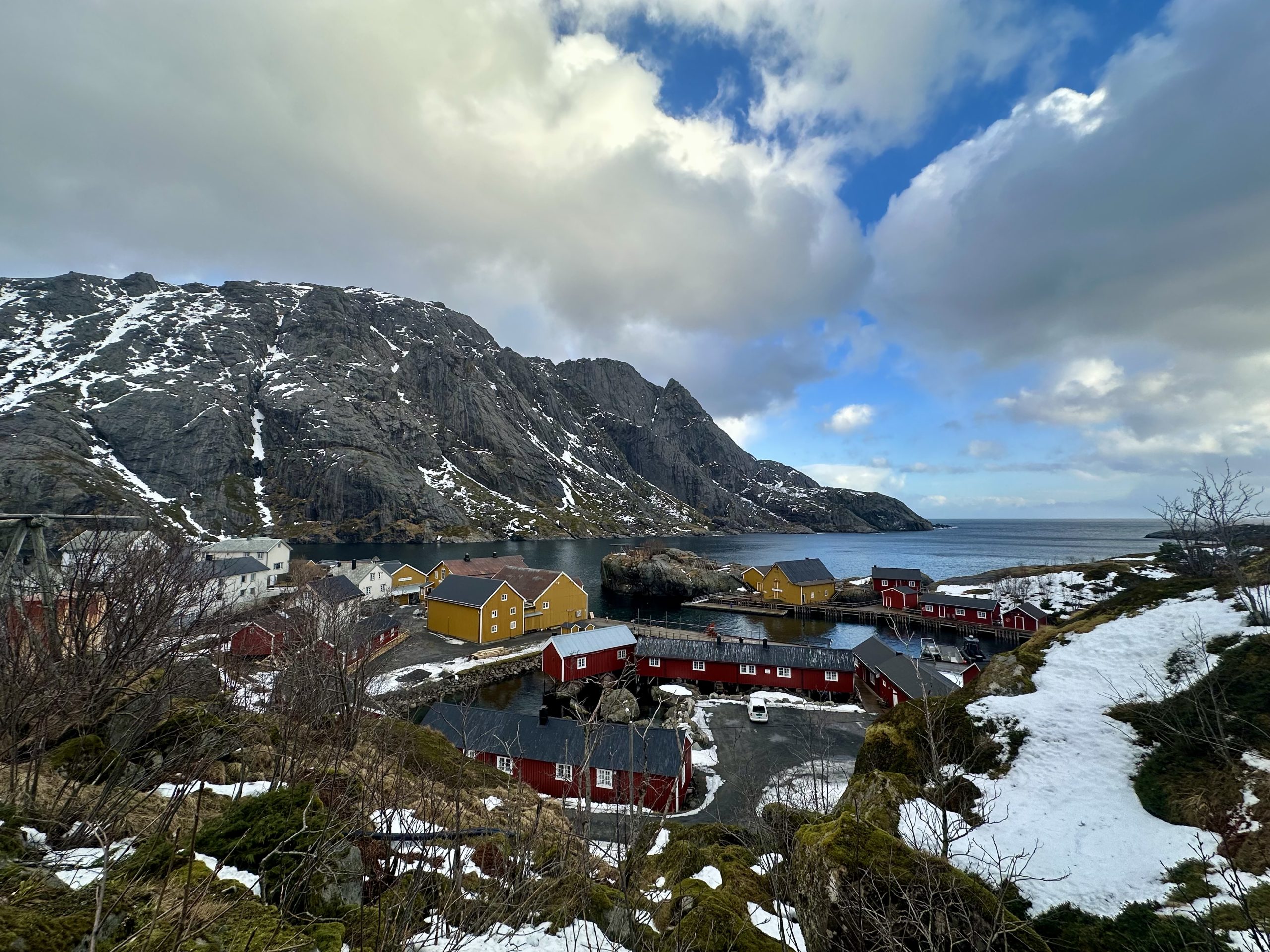 Vista panorámica de Nusfjord con casas rojas, casas amarillas y montañas nevadas