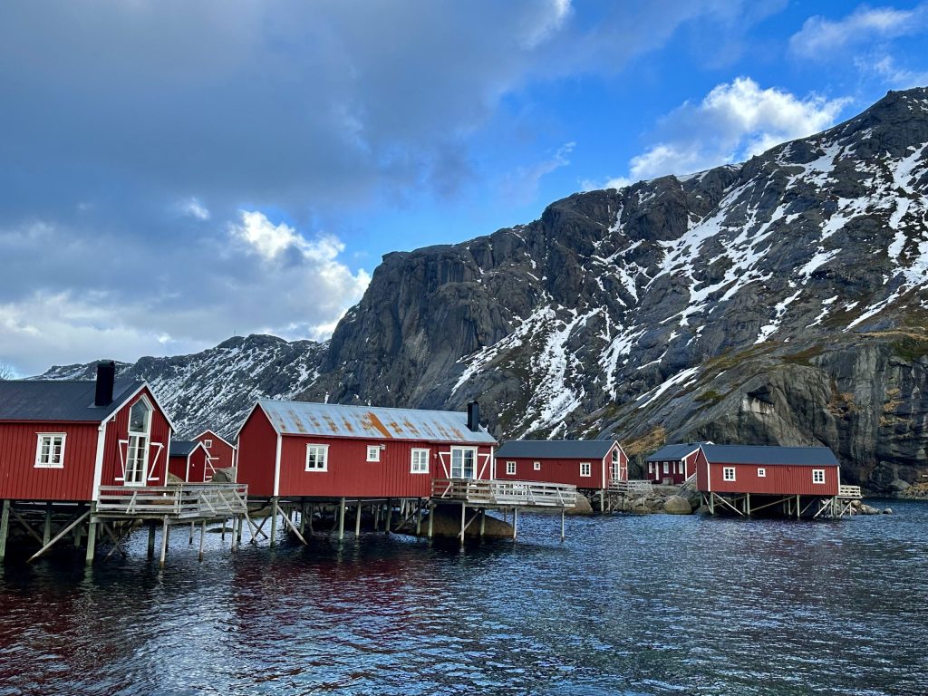 Cabañas tradicionales de Nusfjord frente al fiordo y montañas nevadas de Lofoten