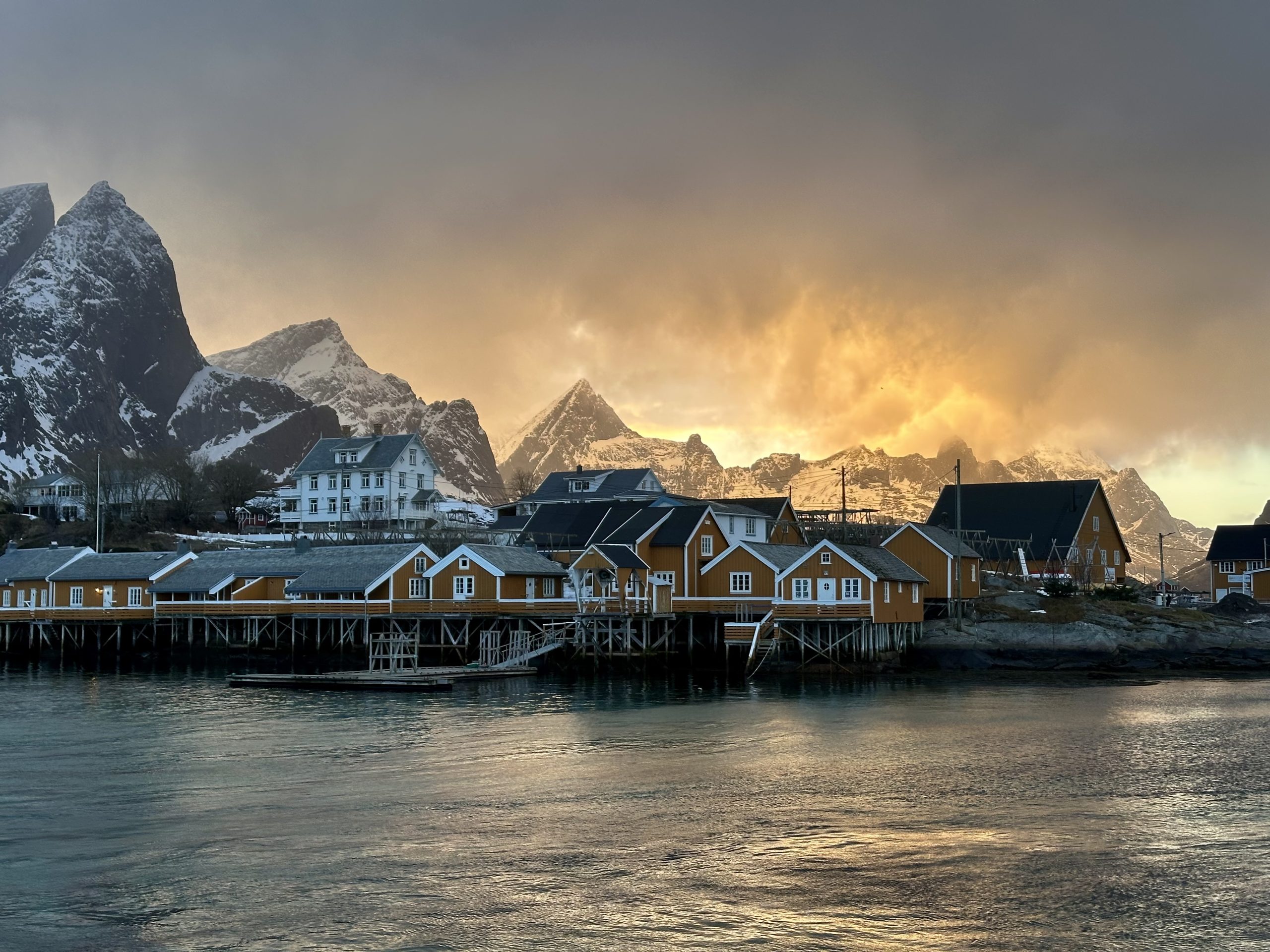Cabañas amarillas de Sakrisøy al atardecer con montañas nevadas de Lofoten al fondo