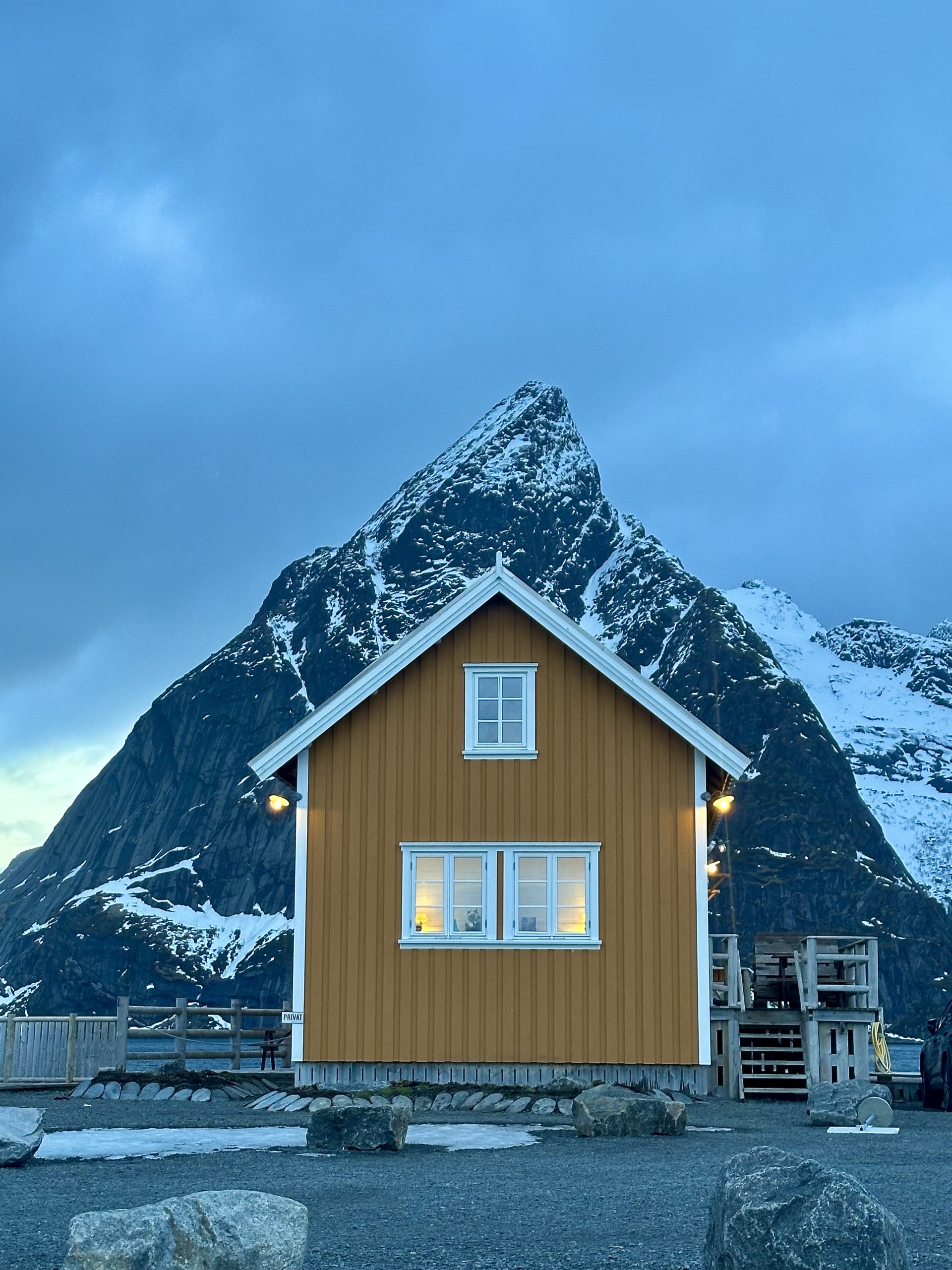 Cabaña amarilla en Sakrisøy con montaña nevada al fondo en las Islas Lofoten