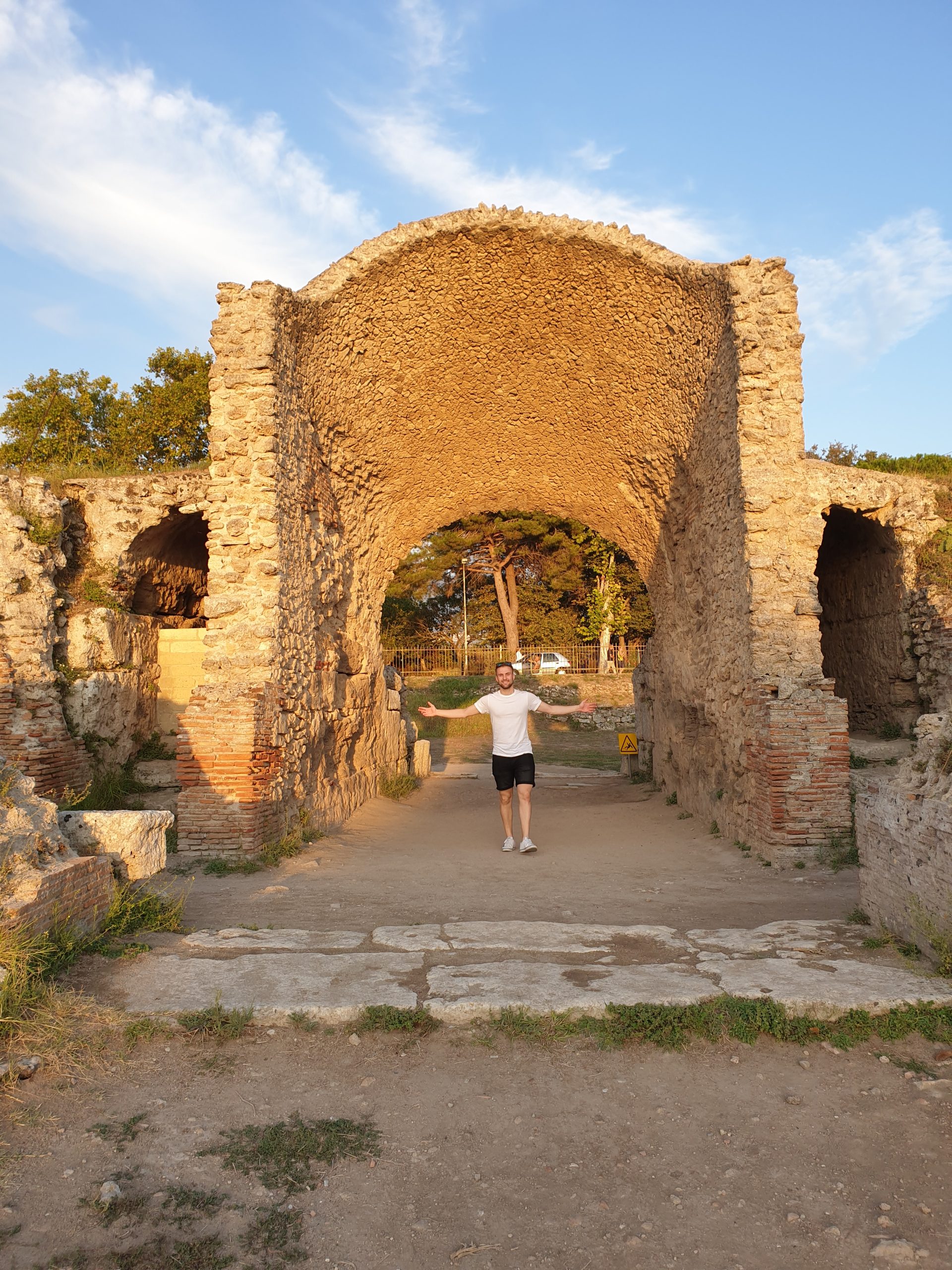 Restos del anfiteatro romano de Paestum con arco de piedra iluminado al atardecer.