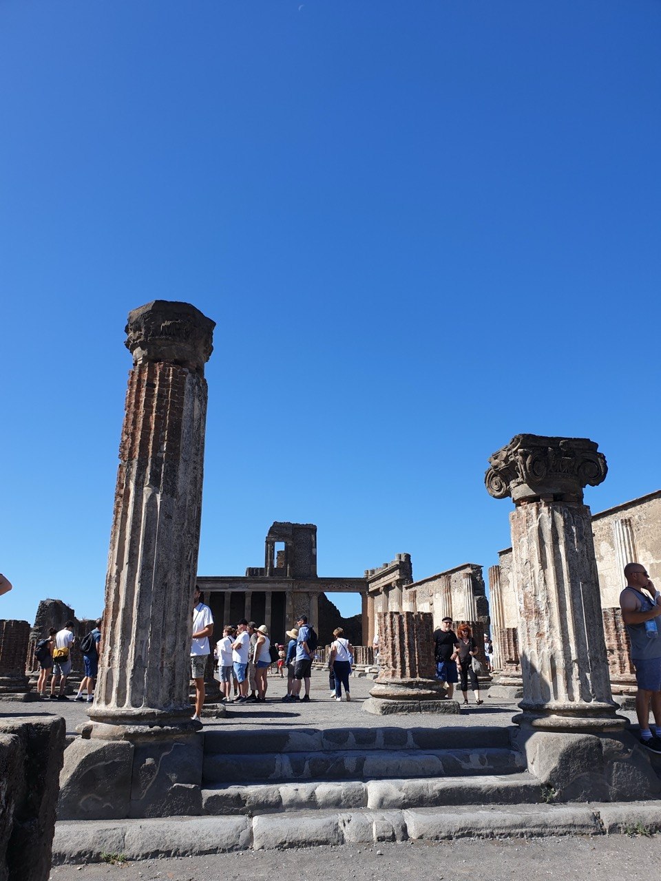 Columnas del Foro de Pompeya con visitantes recorriendo la ciudad romana.