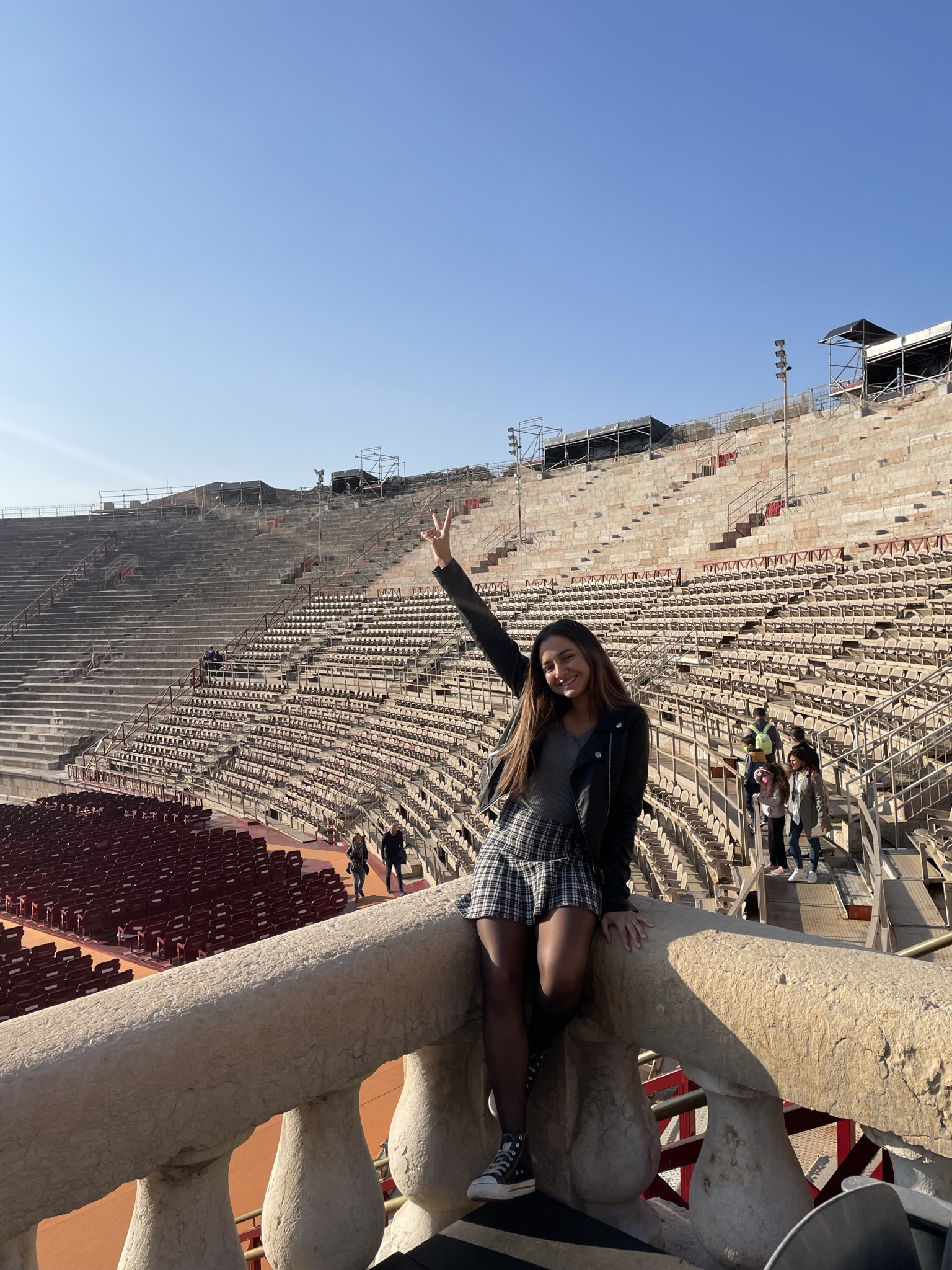 Interior de la Arena de Verona con las gradas del anfiteatro romano y una viajera posando durante la visita.