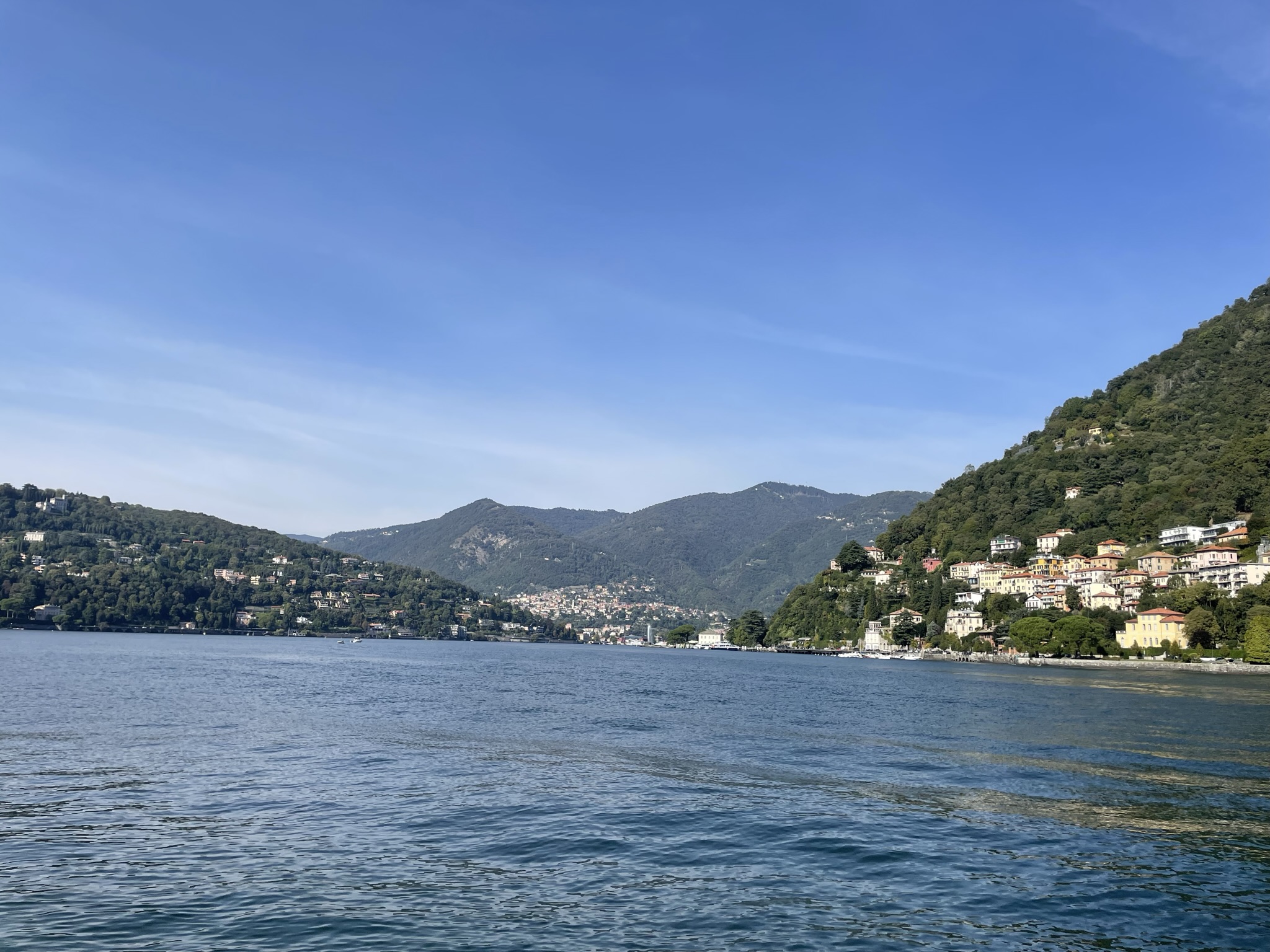 Vistas del Lago di Como desde el paseo de Como con montañas y casas junto al agua