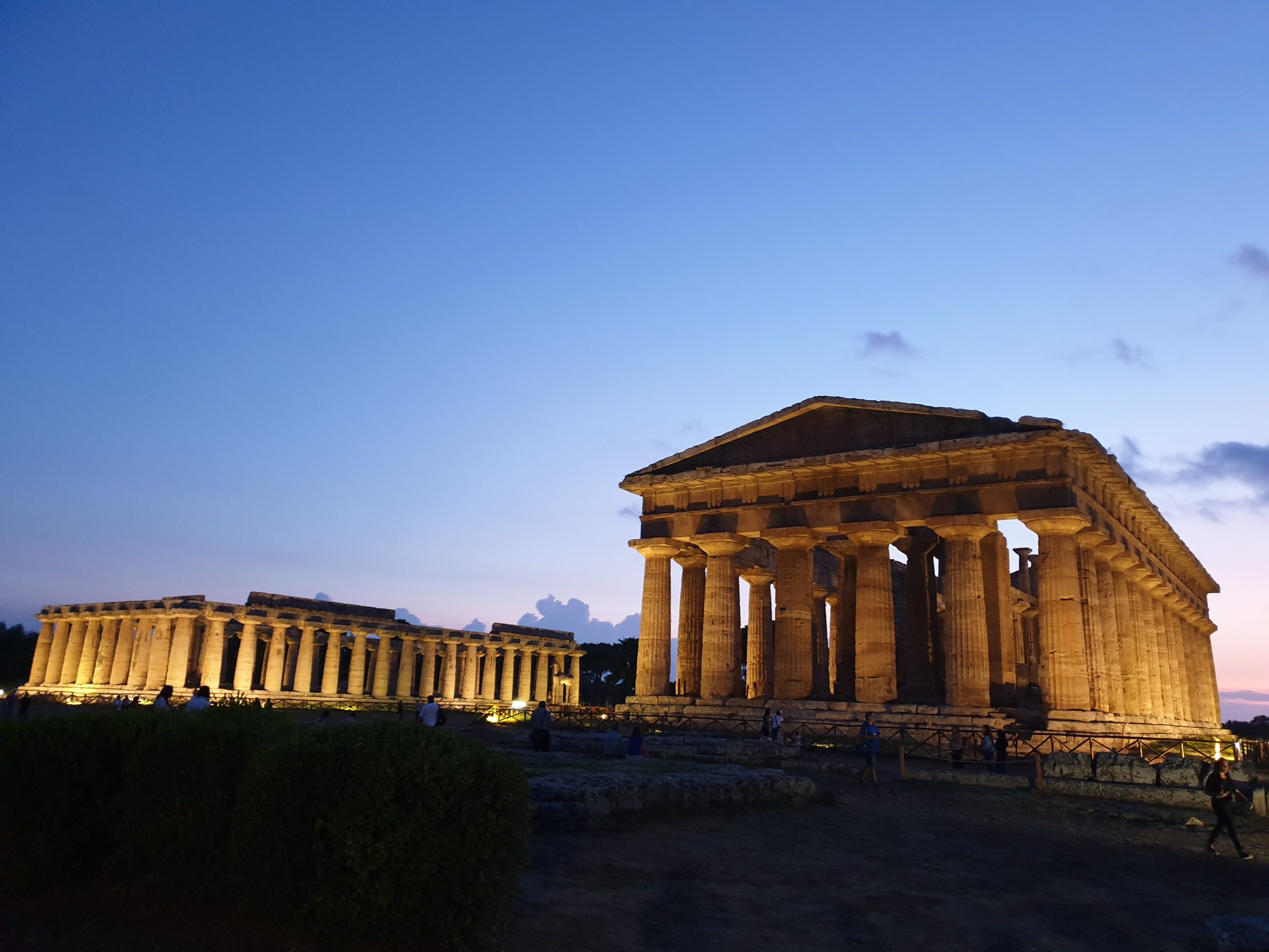 Templos griegos de Paestum iluminados al atardecer dentro del parque arqueológico.