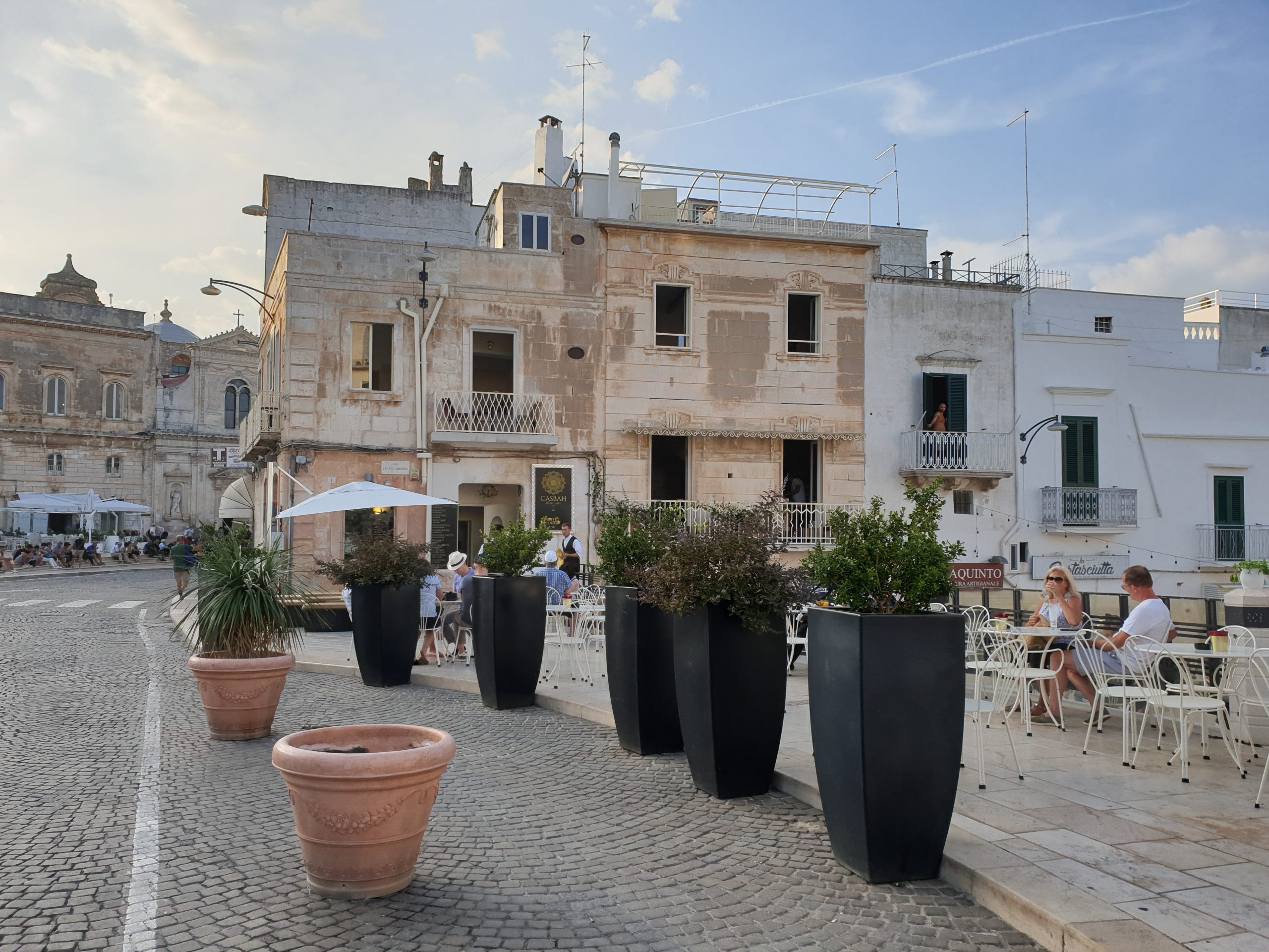Piazza della Libertà de Ostuni con terrazas, edificios históricos y ambiente local.