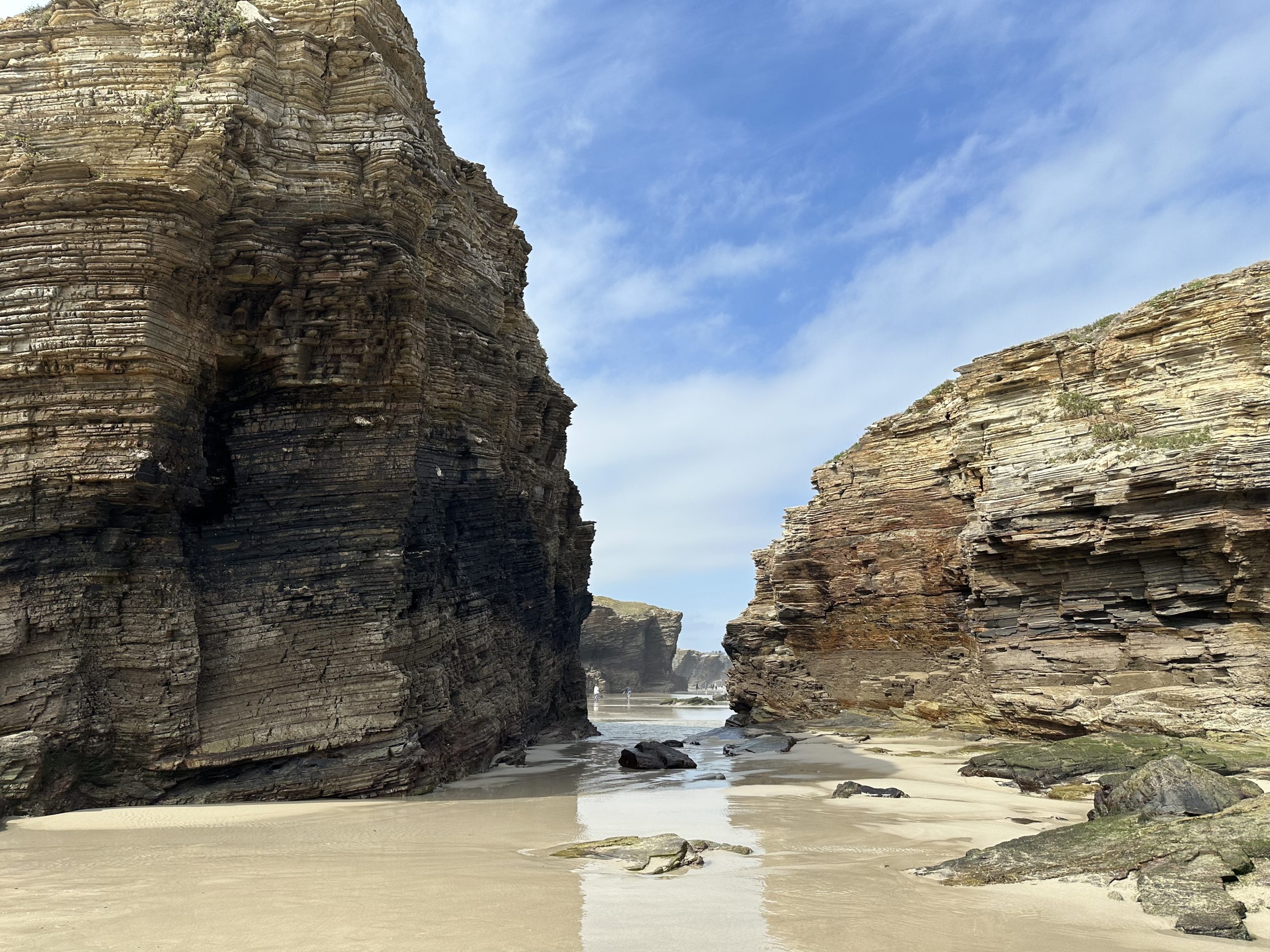 Acantilados de la Playa de las Catedrales con formaciones rocosas y arena mojada