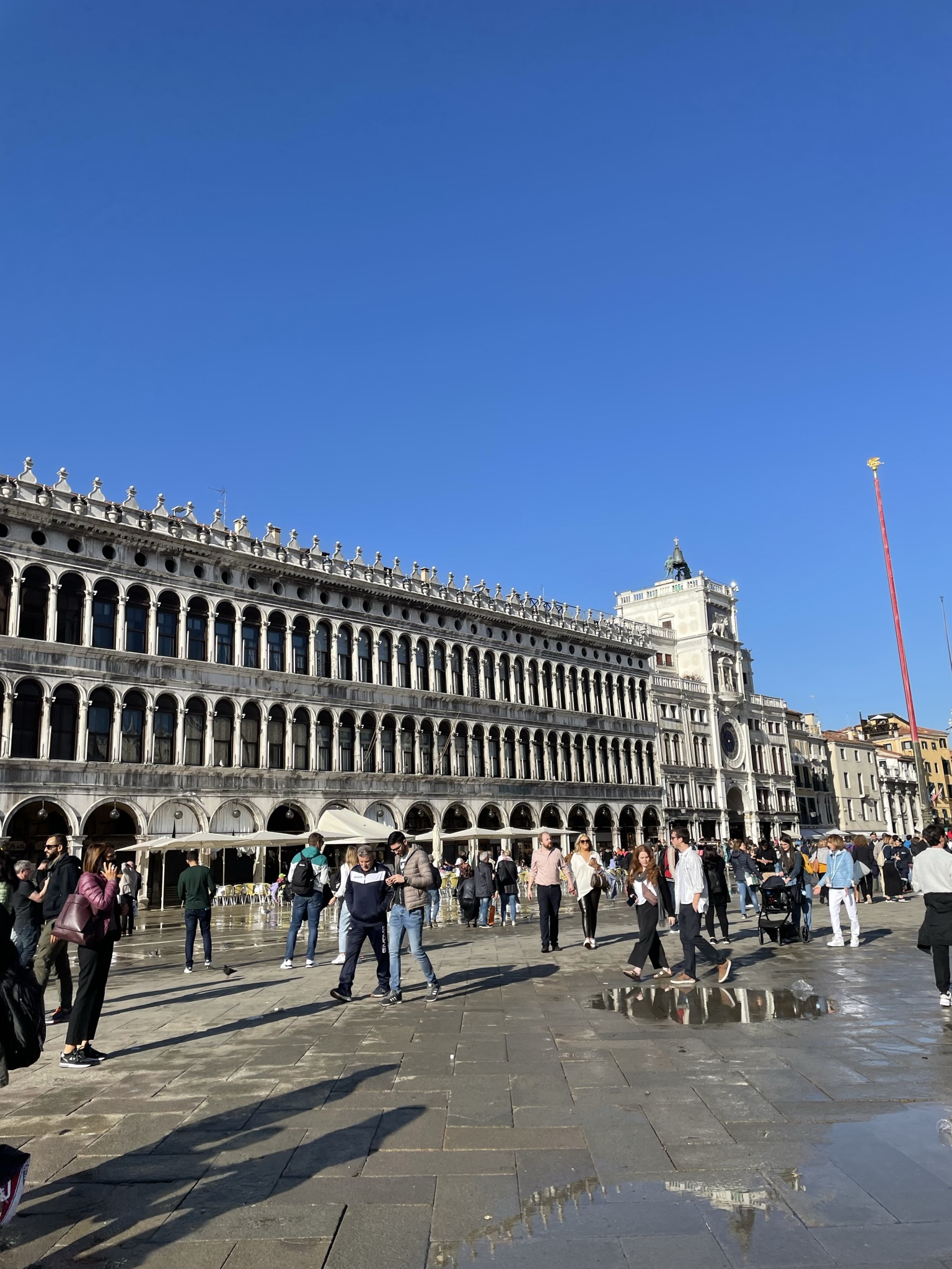 Plaza de San Marcos de Venecia con las Procuratie Vecchie, la Torre del Reloj y ambiente turístico.