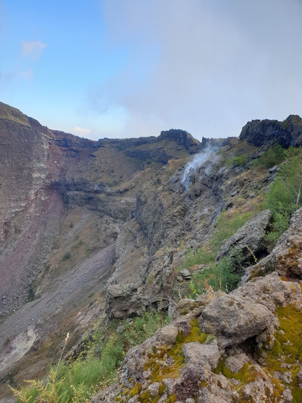 Interior del cráter del Vesubio con humo volcánico y rocas.