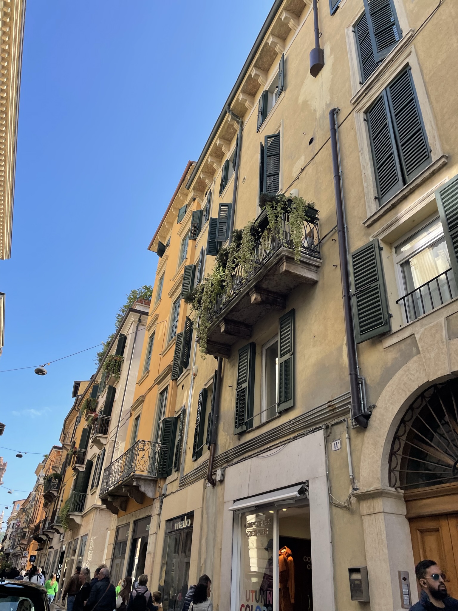 Via Giuseppe Mazzini en Verona, calle comercial del centro histórico con fachadas antiguas y balcones.
